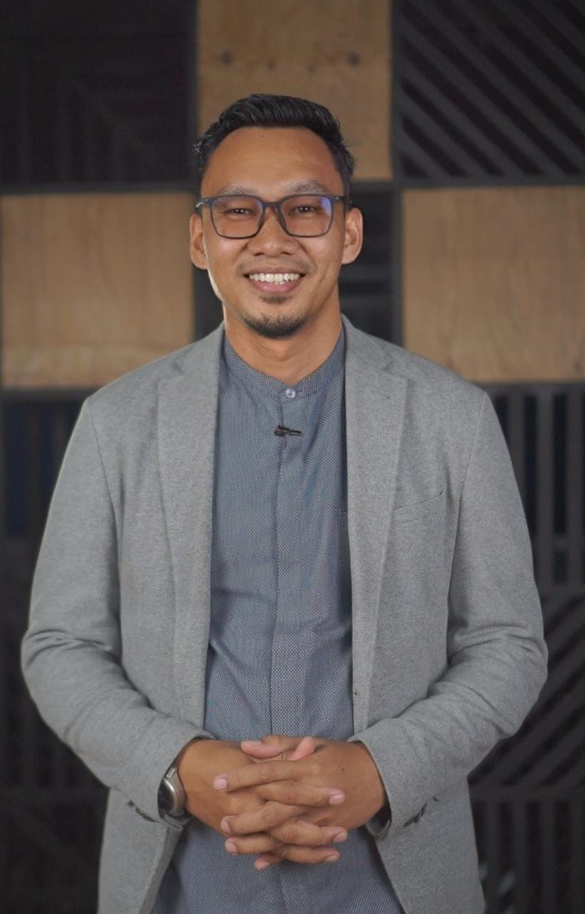 Heri Maulana, Talent & Productivity Coach, tersenyum mengenakan blazer abu-abu